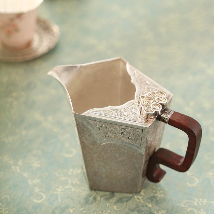 Decorative silver pitcher on a patterned tablecloth