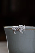 Silver bull-shaped object on a ceramic cup with a dark background